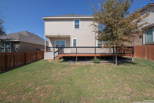 rear view of property featuring a wooden deck and a lawn