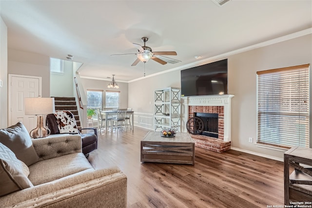 living room featuring ceiling fan, wood-type flooring, ornamental molding, and a fireplace