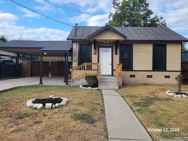 bungalow featuring crawl space, a front lawn, a carport, a fire pit, and fence