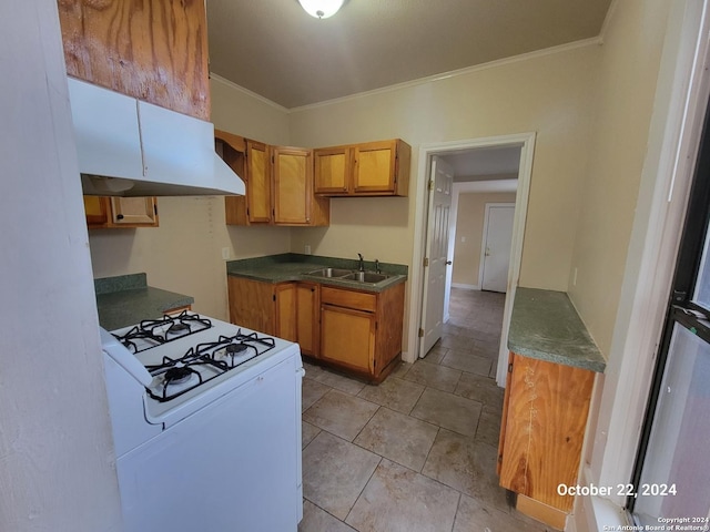 kitchen featuring dark countertops, white range with gas stovetop, ornamental molding, and a sink