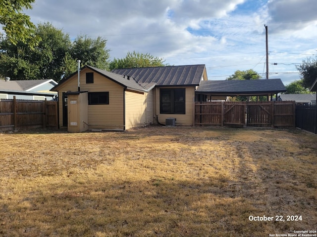 rear view of house with a fenced backyard, central air condition unit, and a lawn