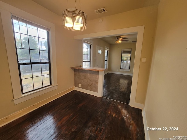 unfurnished dining area with visible vents, baseboards, dark wood-style floors, and ceiling fan with notable chandelier