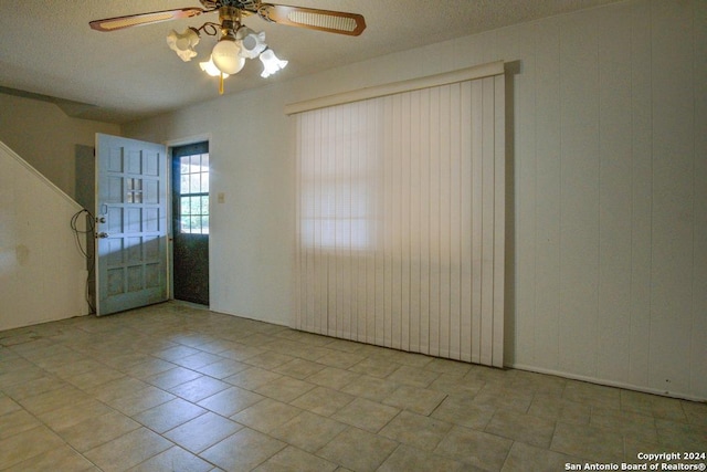 unfurnished room with a textured ceiling, light tile patterned floors, and ceiling fan