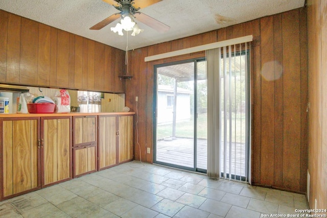 kitchen featuring ceiling fan, a textured ceiling, and wood walls