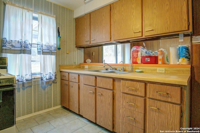 kitchen featuring light tile patterned floors, electric range oven, and sink