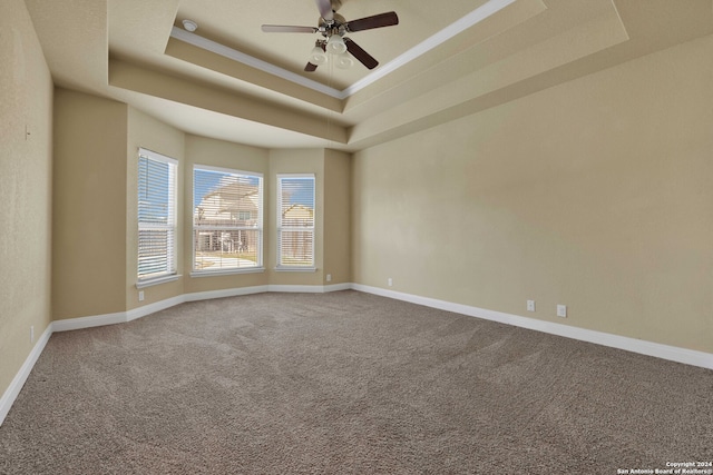 empty room featuring ceiling fan, a raised ceiling, and carpet flooring