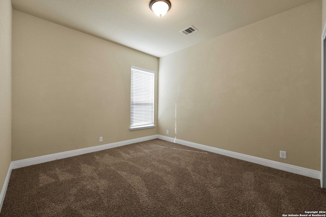 empty room with carpet and a textured ceiling