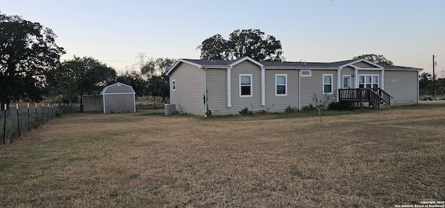 view of front facade featuring central AC, a storage shed, and a front lawn