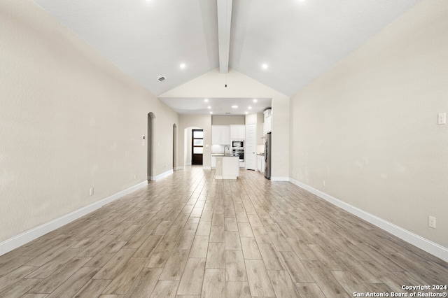 unfurnished living room with sink, light hardwood / wood-style flooring, and vaulted ceiling with beams