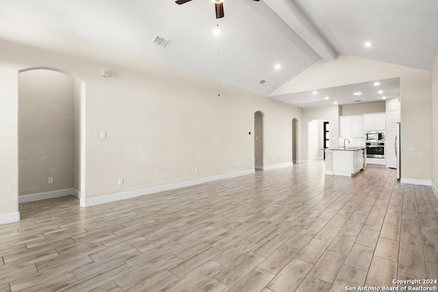 unfurnished living room with light hardwood / wood-style floors, lofted ceiling with beams, sink, and ceiling fan