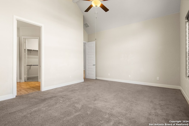 unfurnished bedroom with carpet floors, a spacious closet, high vaulted ceiling, and ceiling fan