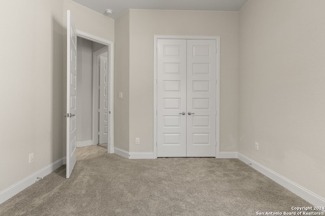 unfurnished bedroom featuring a closet and light colored carpet