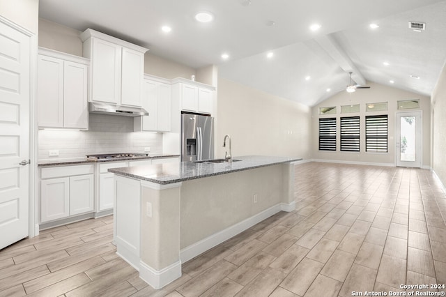 kitchen featuring a kitchen island with sink, vaulted ceiling with beams, stainless steel appliances, sink, and light wood-type flooring