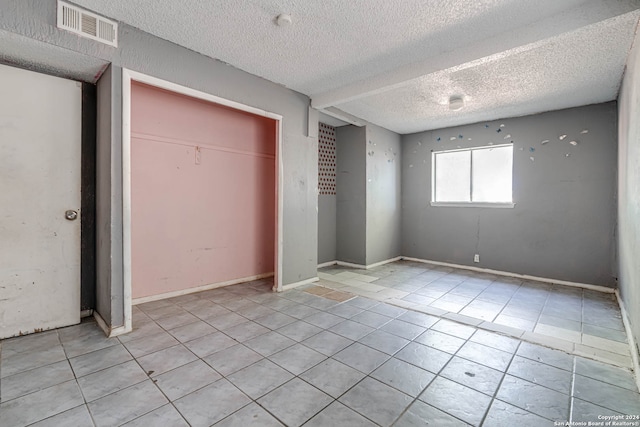 unfurnished bedroom featuring a closet, a textured ceiling, and light tile patterned flooring