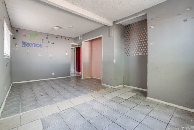 unfurnished room featuring a textured ceiling and light tile patterned floors