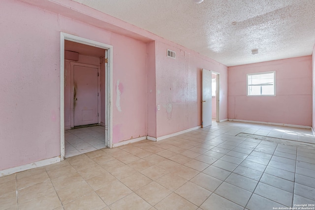 tiled empty room with a textured ceiling