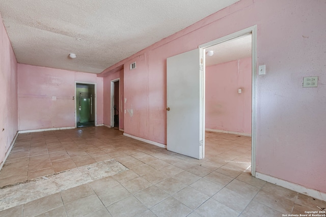 tiled spare room with a textured ceiling