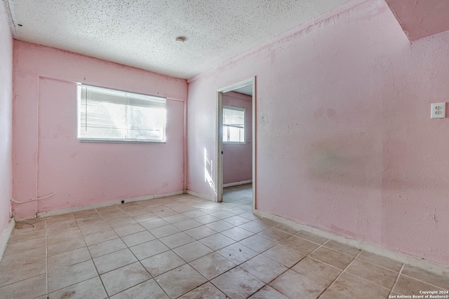 tiled spare room with a textured ceiling