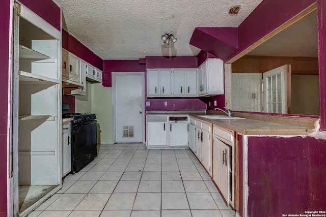 kitchen featuring black gas range, white cabinets, and light tile patterned floors