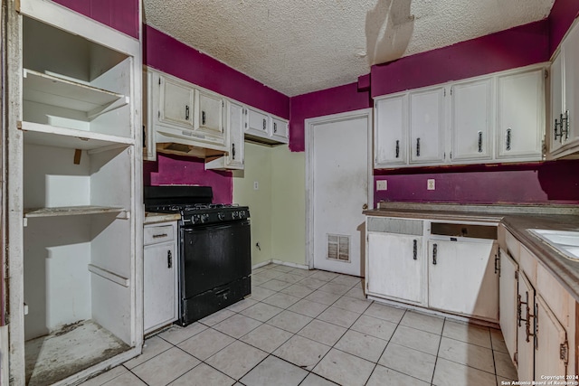 kitchen with a textured ceiling, white cabinets, gas stove, and light tile patterned floors