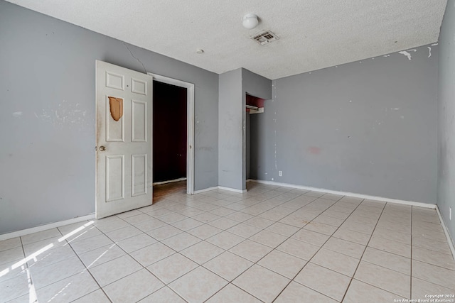 unfurnished bedroom featuring a closet, a textured ceiling, and light tile patterned floors