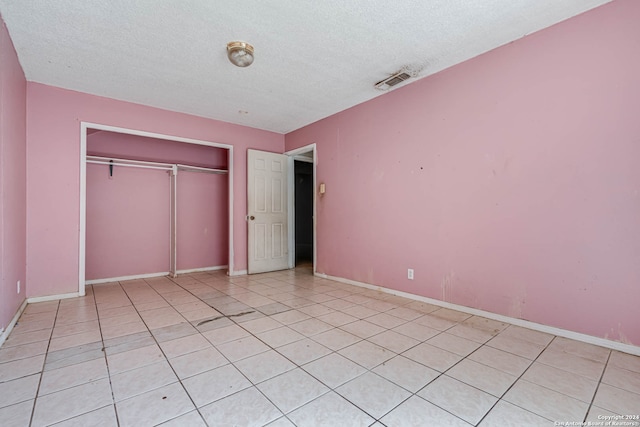 unfurnished bedroom featuring a closet, a textured ceiling, and light tile patterned floors