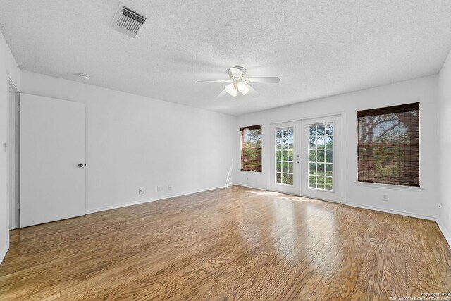 unfurnished room featuring ceiling fan, a textured ceiling, light wood-type flooring, and french doors