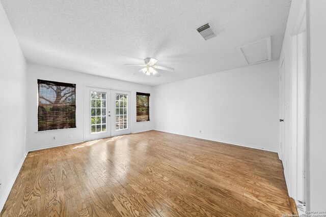 unfurnished room with french doors, light hardwood / wood-style floors, and a textured ceiling