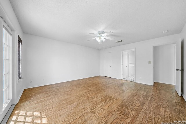 spare room with ceiling fan, a textured ceiling, and light hardwood / wood-style floors