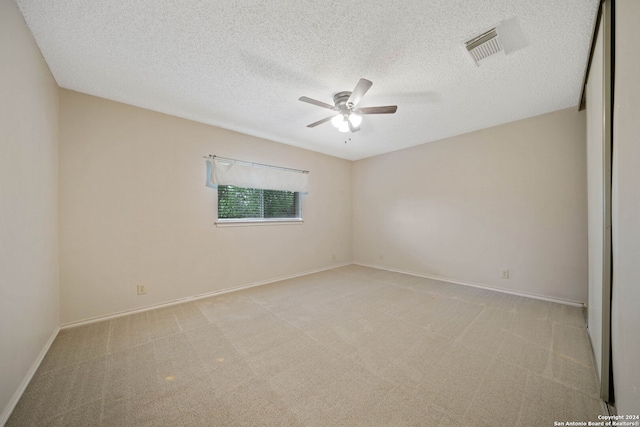 empty room with light colored carpet, a textured ceiling, and ceiling fan