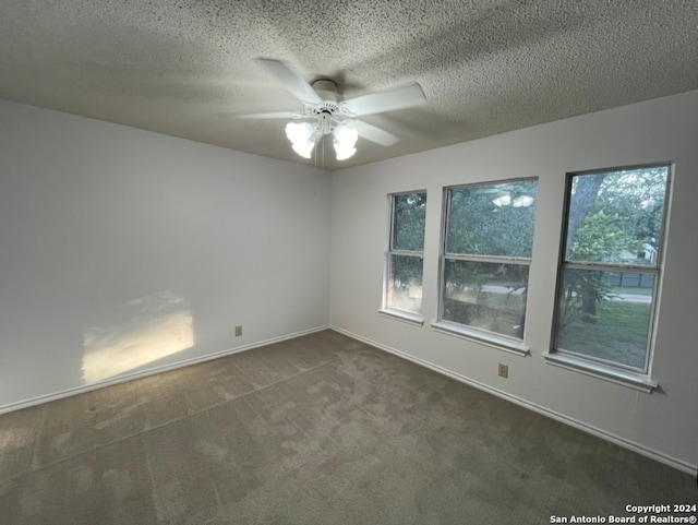 unfurnished room with a textured ceiling, dark colored carpet, and ceiling fan