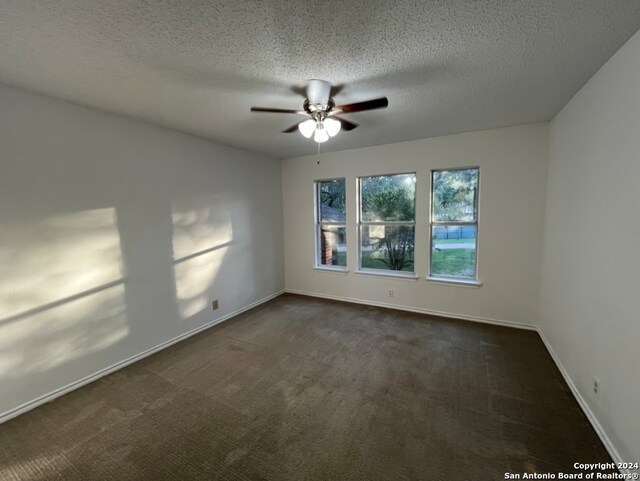 carpeted empty room featuring ceiling fan and a textured ceiling