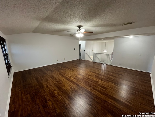 spare room featuring dark wood-type flooring, a textured ceiling, and vaulted ceiling