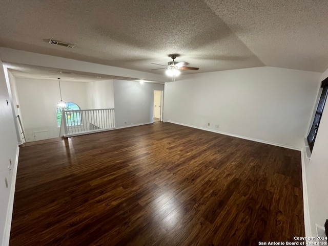 empty room featuring dark hardwood / wood-style flooring, lofted ceiling, a textured ceiling, and ceiling fan with notable chandelier