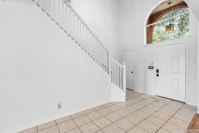 entryway with light tile patterned floors and a towering ceiling