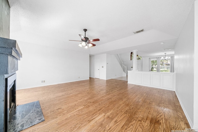 unfurnished living room with ceiling fan with notable chandelier, a textured ceiling, and light hardwood / wood-style flooring