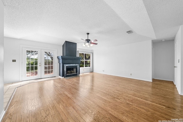 unfurnished living room with light wood-type flooring, a textured ceiling, ceiling fan, and french doors