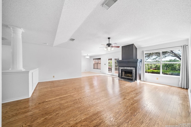 unfurnished living room featuring ornate columns, a premium fireplace, light hardwood / wood-style floors, and a textured ceiling