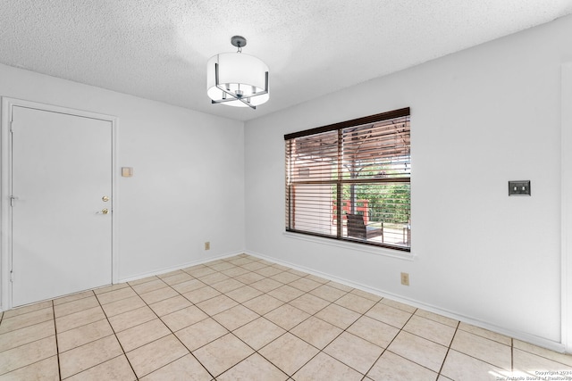 unfurnished room with an inviting chandelier, a textured ceiling, and light tile patterned floors