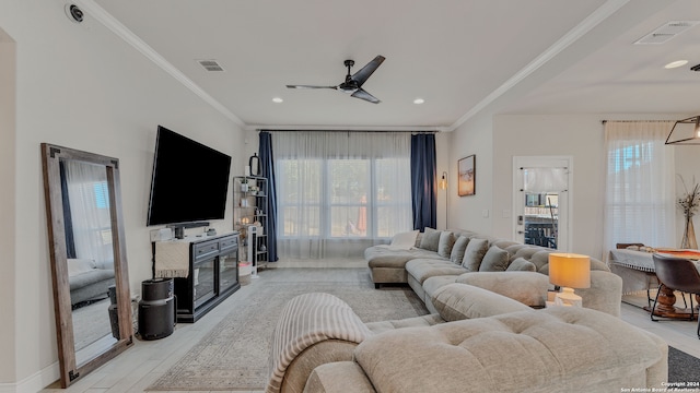 living room with ornamental molding, ceiling fan, light wood-type flooring, and a wealth of natural light