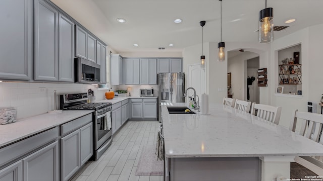 kitchen featuring a large island, a kitchen breakfast bar, sink, gray cabinets, and stainless steel appliances