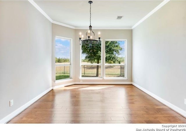 unfurnished dining area with ornamental molding, hardwood / wood-style flooring, a chandelier, and plenty of natural light