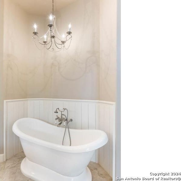 bathroom with a chandelier and a bath