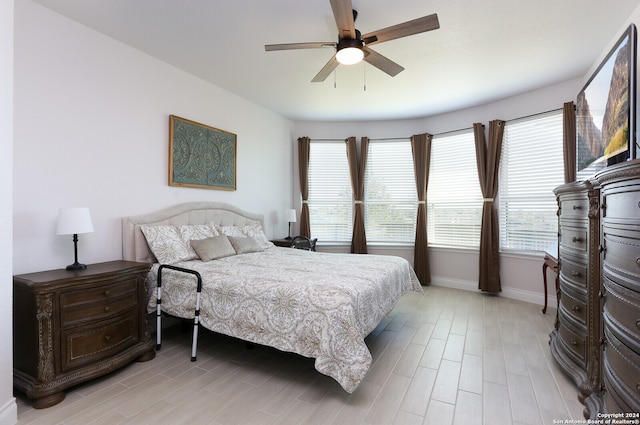 bedroom with multiple windows, light hardwood / wood-style floors, and ceiling fan