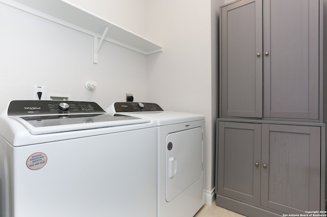 clothes washing area featuring cabinets and washer and dryer