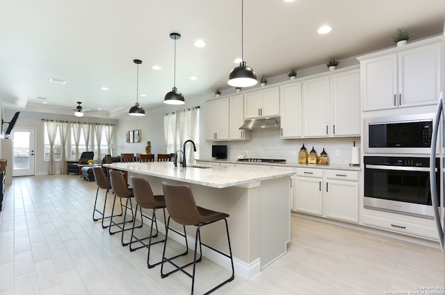 kitchen featuring white cabinetry, pendant lighting, and an island with sink