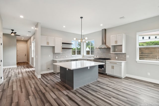 kitchen featuring wall chimney range hood, white cabinetry, a center island, and high end stainless steel range oven