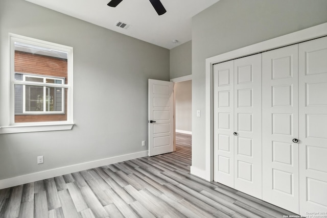 unfurnished bedroom with light hardwood / wood-style floors, a closet, and ceiling fan