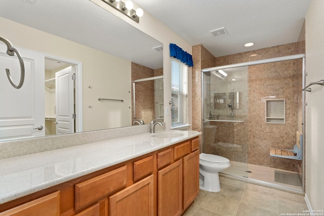 bathroom featuring toilet, tile patterned flooring, vanity, a textured ceiling, and an enclosed shower