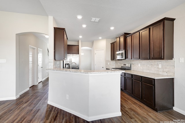 kitchen featuring a center island with sink, appliances with stainless steel finishes, light stone counters, and dark hardwood / wood-style flooring